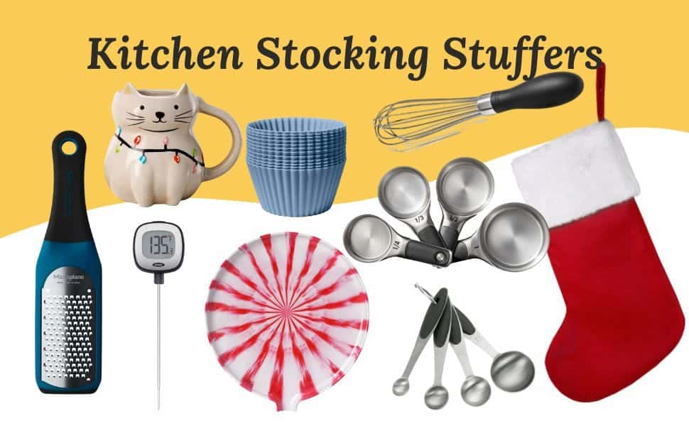 Kitchen Stocking Stuffers gift guide with small kitchen tools and accessories. Items include a festive cat mug with holiday lights, a set of silicone baking cups, a small whisk, a red and white striped plate, a digital cooking thermometer, a mini hand grater, a set of metal measuring cups, a set of metal measuring spoons, and a red Christmas stocking. The items are arranged on a white and yellow background.