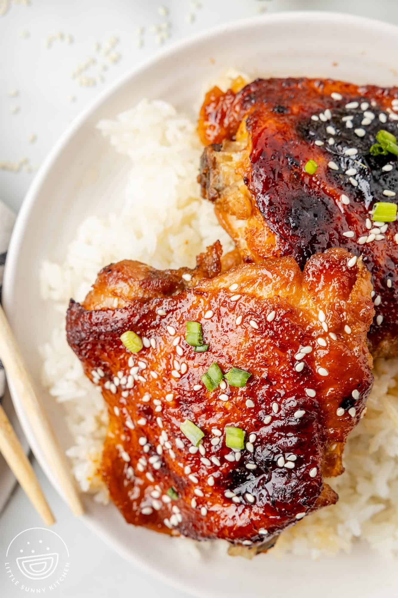 honey soy chicken thighs with crispy skin over a bowl of white rice.