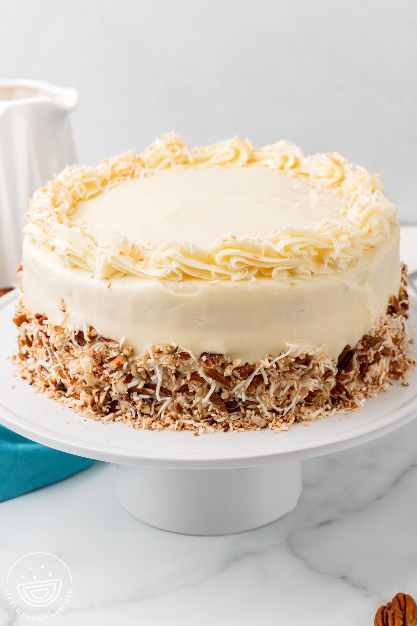 Italian cream cake with piped top border of cream cheese frosting and nuts pressed into the sides.