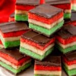 a plate of tri colored Italian rainbow cookies, stacked neatly