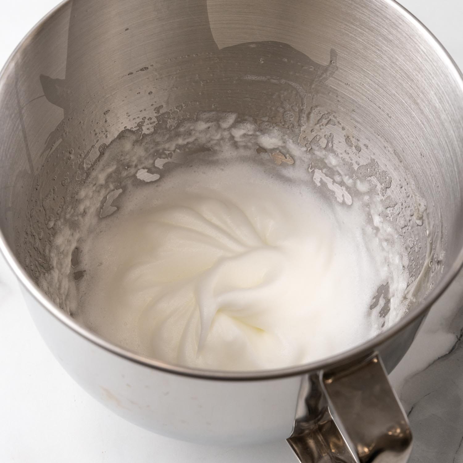 whipped egg whites in a metal mixing bowl.