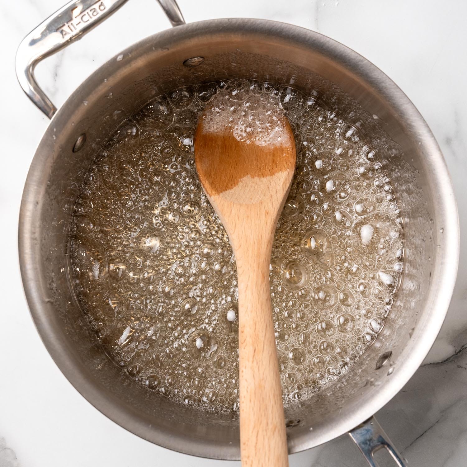 sugar, water, and corn syrup, boiling in a pot with a wooden spoon.