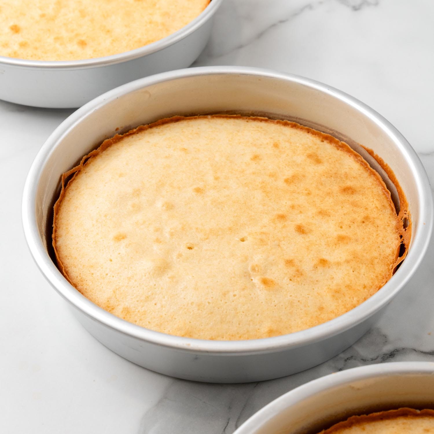 baked lane cake layers in metal baking pans.