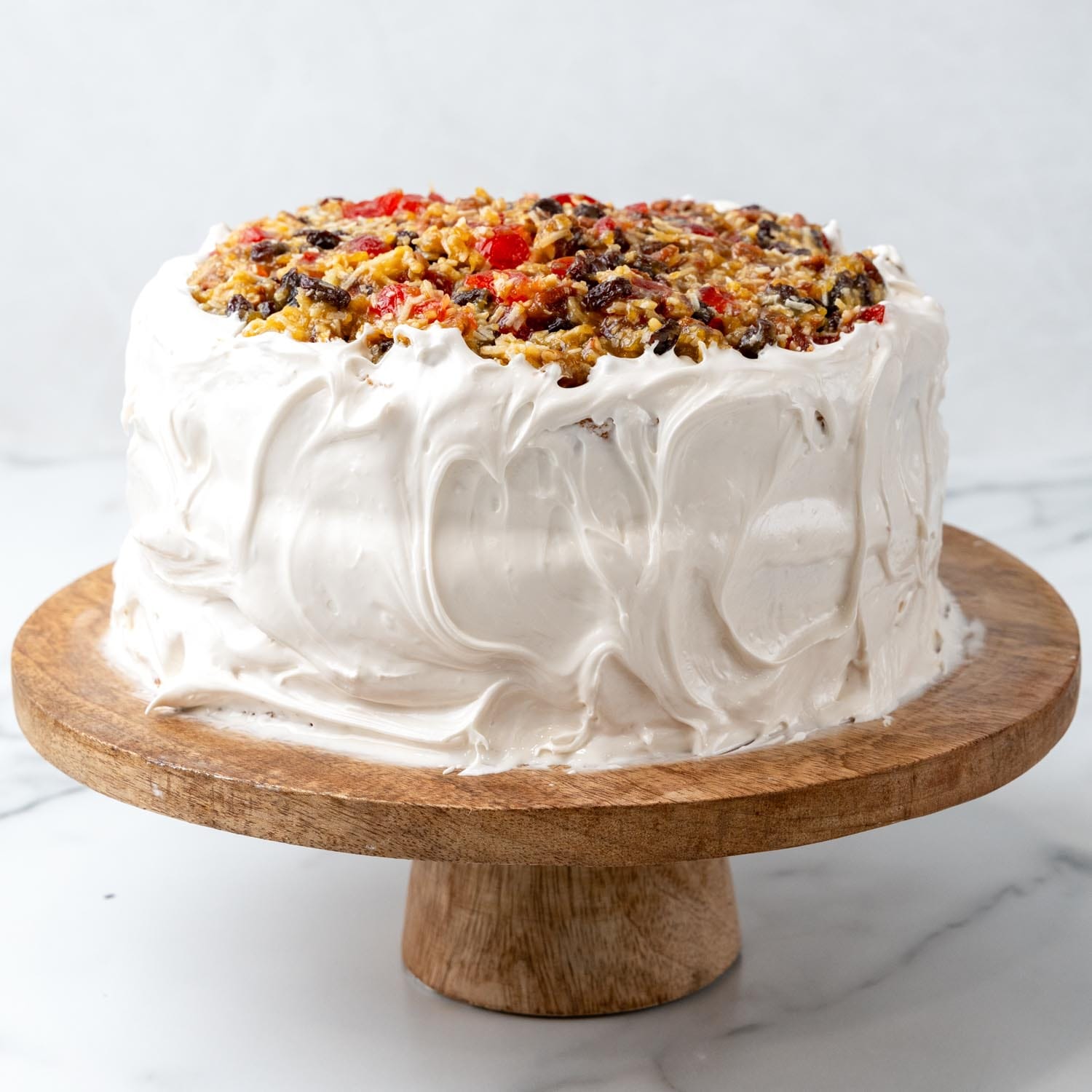 Decorated lane cake with whipped frosting and fruit and nut topping.