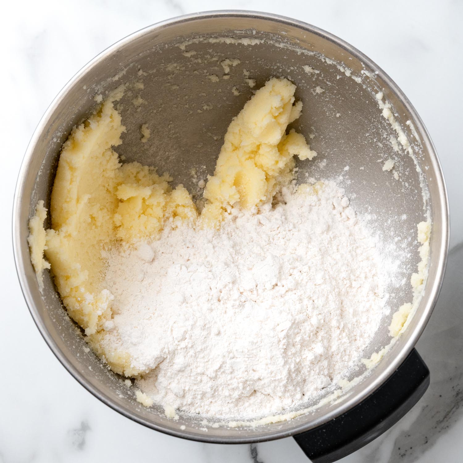 half of the flour added to creamed butter and sugar in a metal mixing bowl.