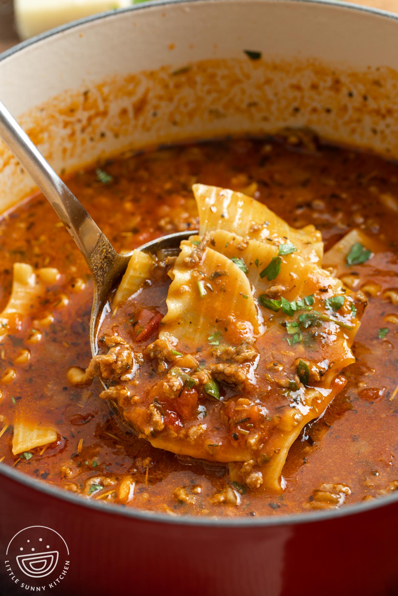 A ladle of lasagna soup and a dutch oven with soup