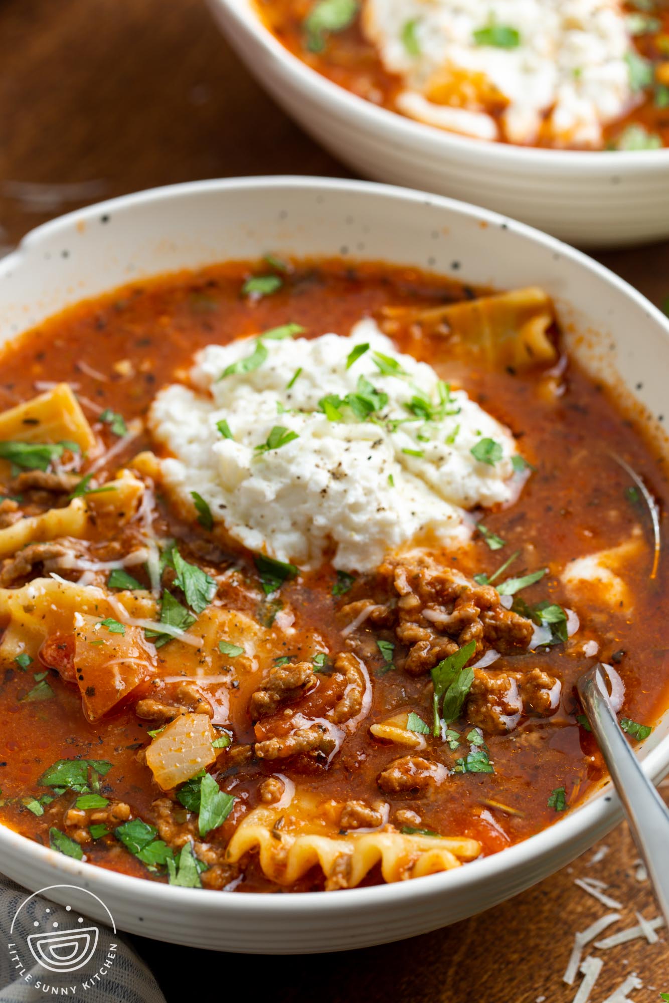 Close up shot of a bowl with lasagna soup and a dollop of ricotta and other cheeses