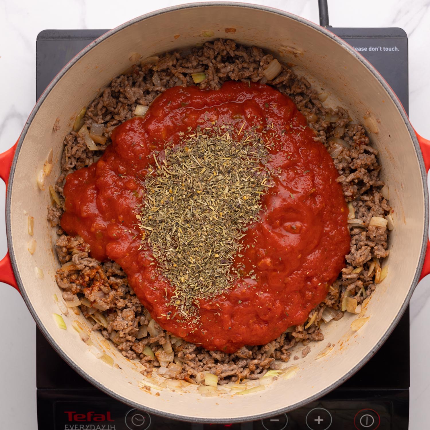 dried Italian seasoning and marinara sauce added to a pot for lasagna soup.