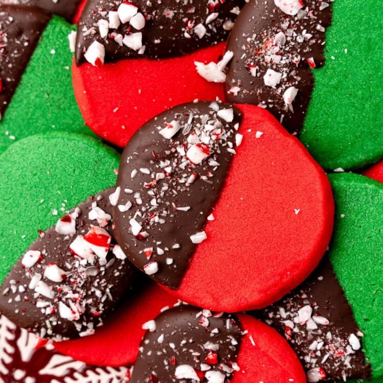 dark red and deep green round shortbread cookies. Each cookie is half dipped in chocolate and decorated with crushed peppermint candy.