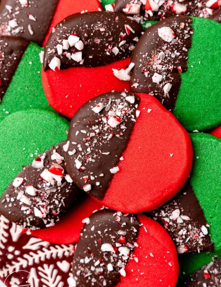 dark red and deep green round shortbread cookies. Each cookie is half dipped in chocolate and decorated with crushed peppermint candy.