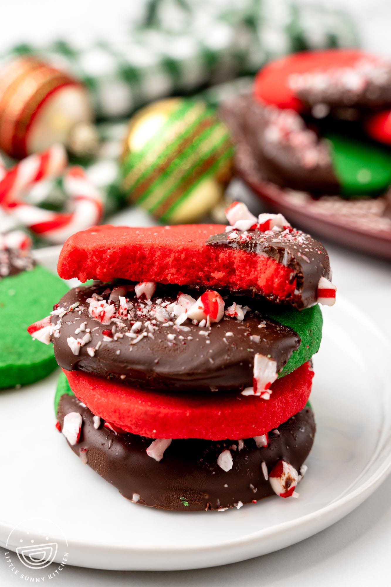 a stack of red and green shortbread cookies, half dipped in chocolate and decorated with crushed candy canes.