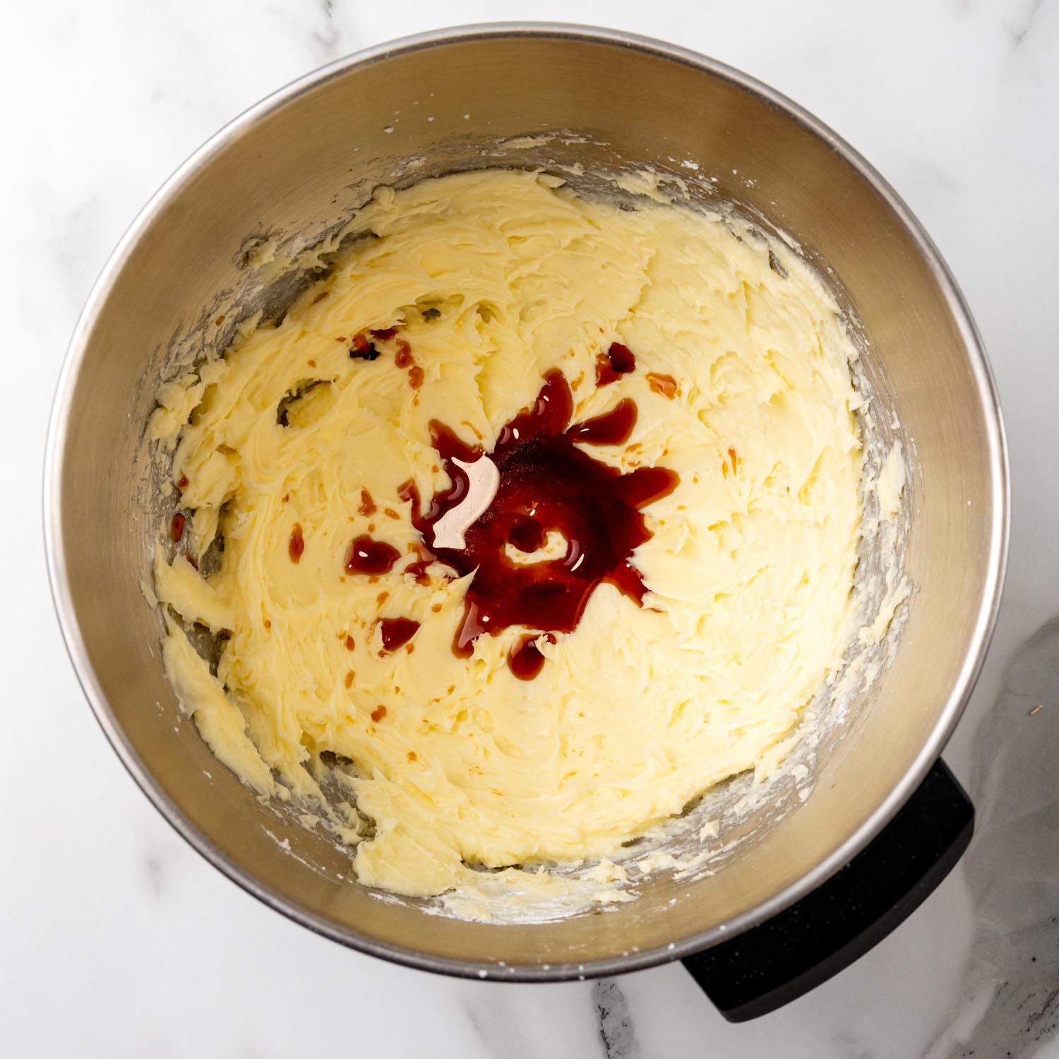 vanilla extract added to creamed butter and sugar in a mixing bowl.