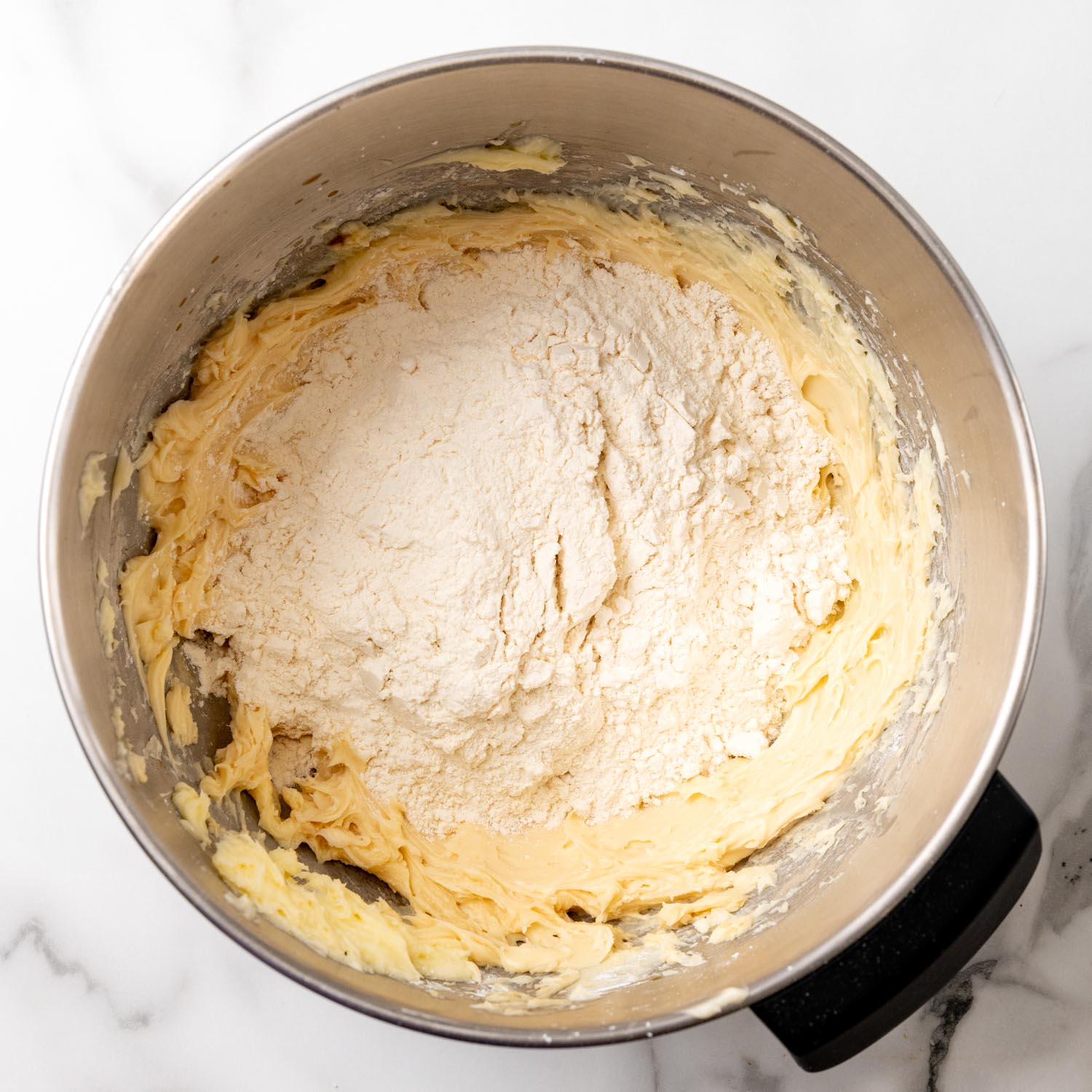 flour added to a mixing bowl of ingredients to make shortbread cookies.