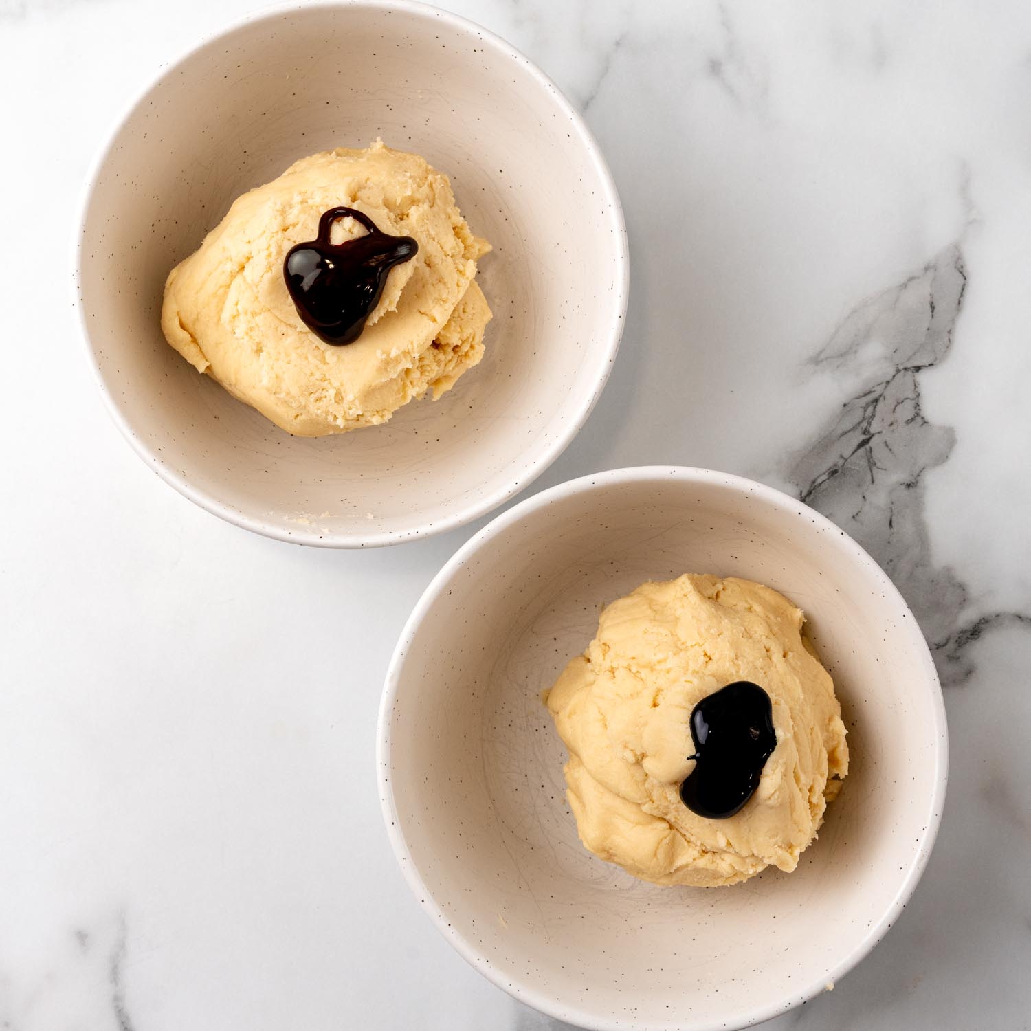 shortbread cookie dough in two separate bowls with gel food coloring on top.