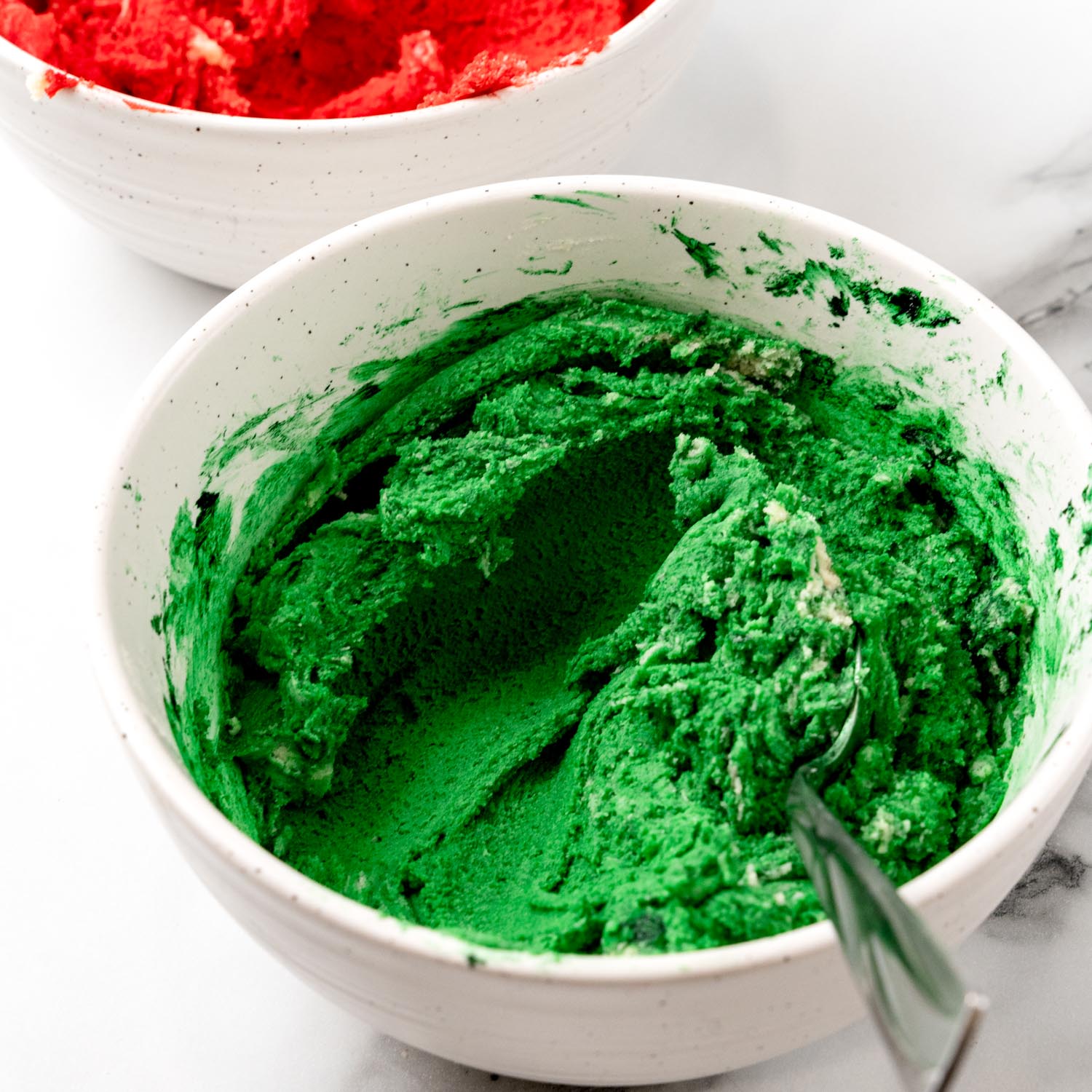 cookie dough dyed green in a white ceramic bowl.