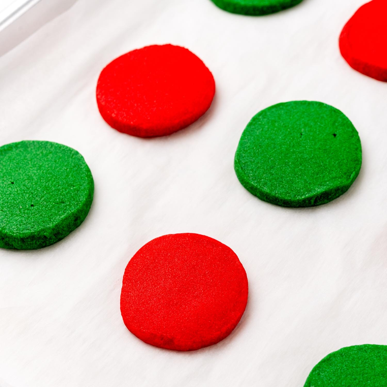 round red and green shortbread cookies on parchment paper.