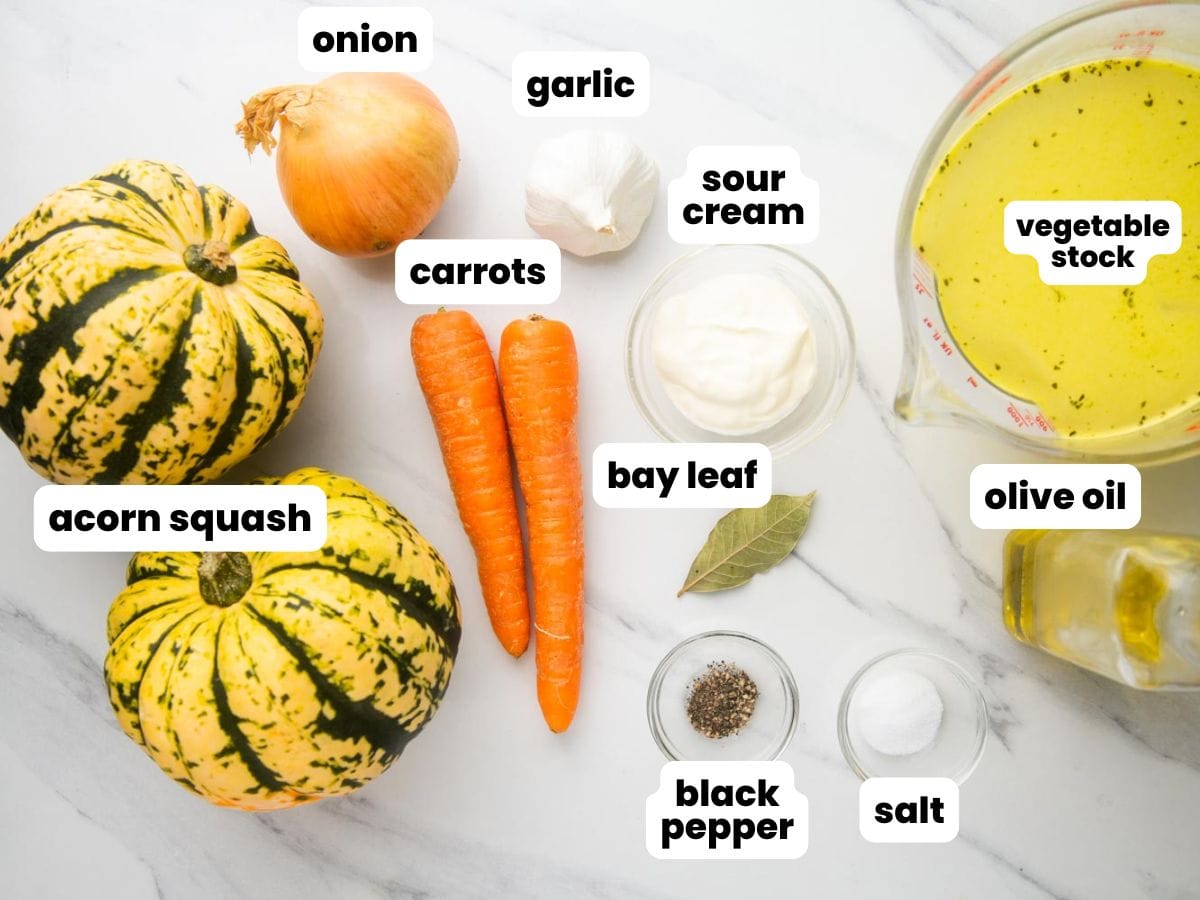 Ingredients for acorn squash soup arranged on a marble counter.