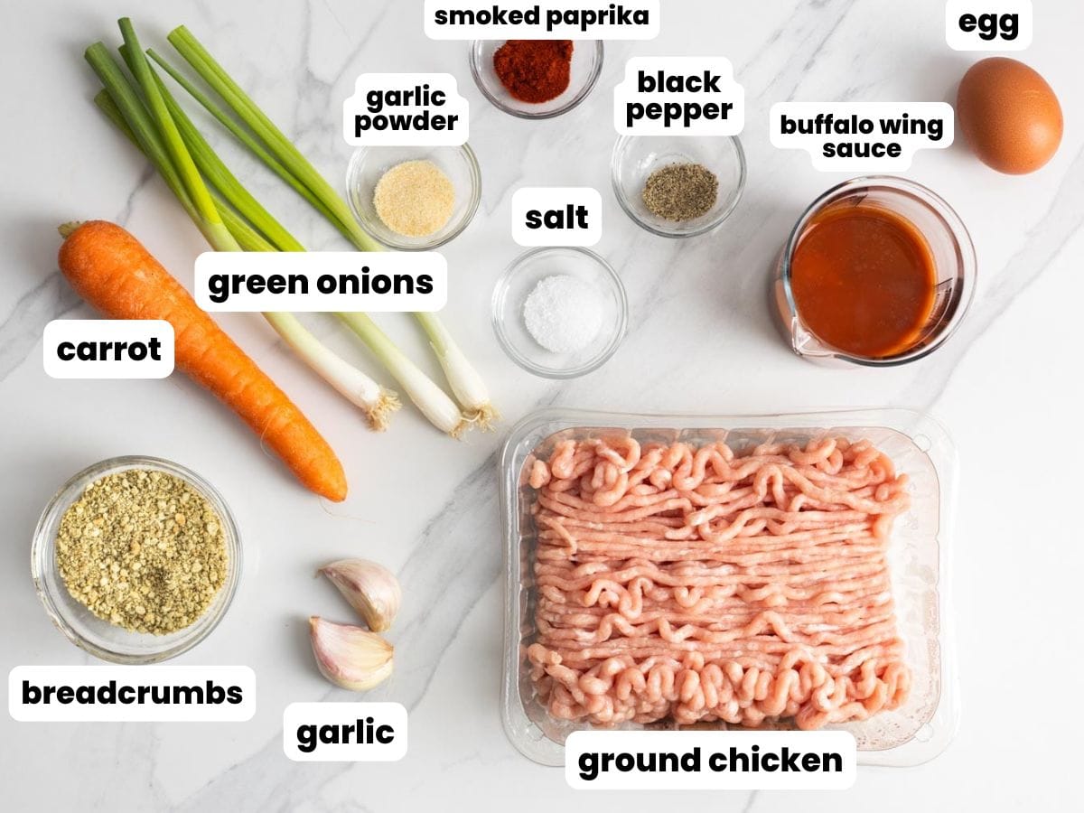 A pound of ground chicken with the ingredients for making buffalo chicken meatballs, arranged on a marble counter.