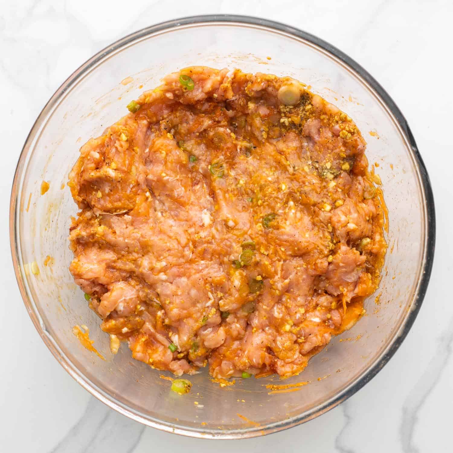 Buffalo chicken meatball raw mixture in a glass mixing bowl.