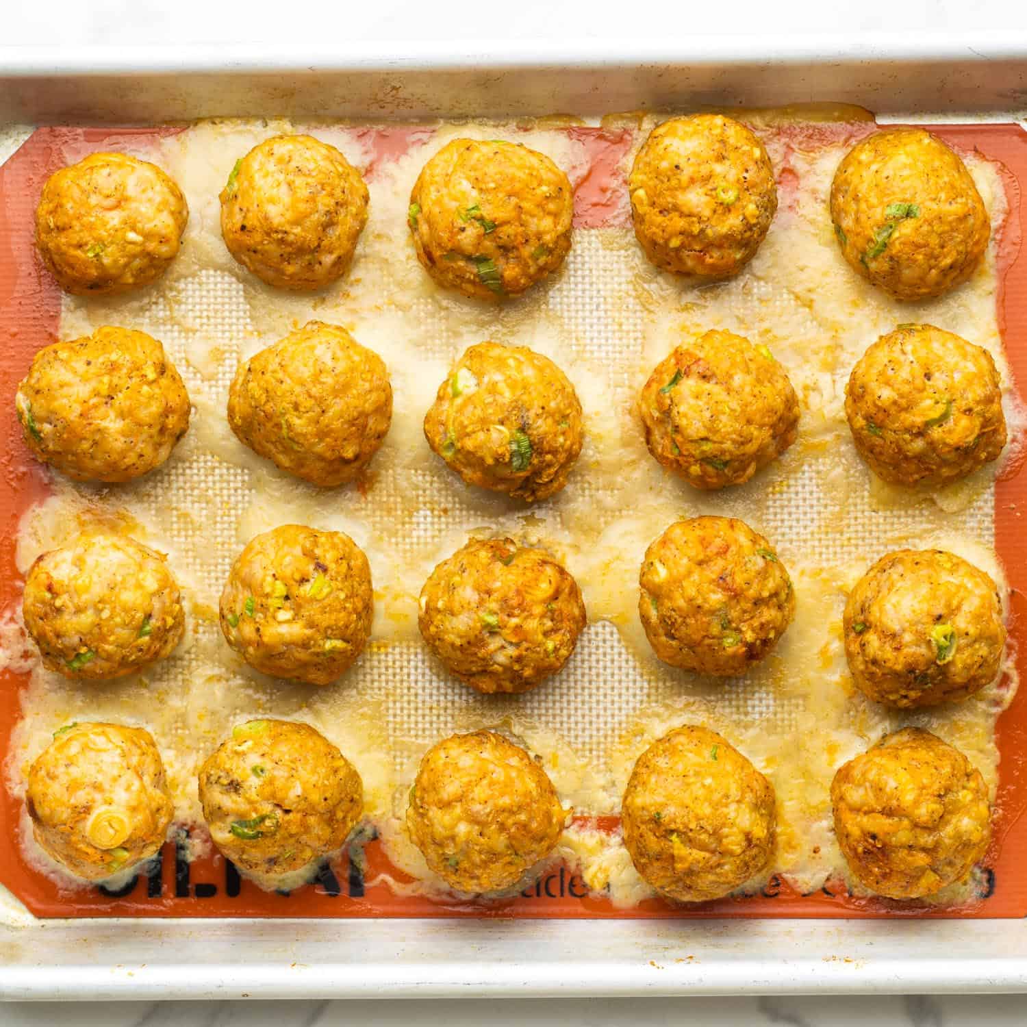 baked buffalo chicken meatballs on a baking tray.