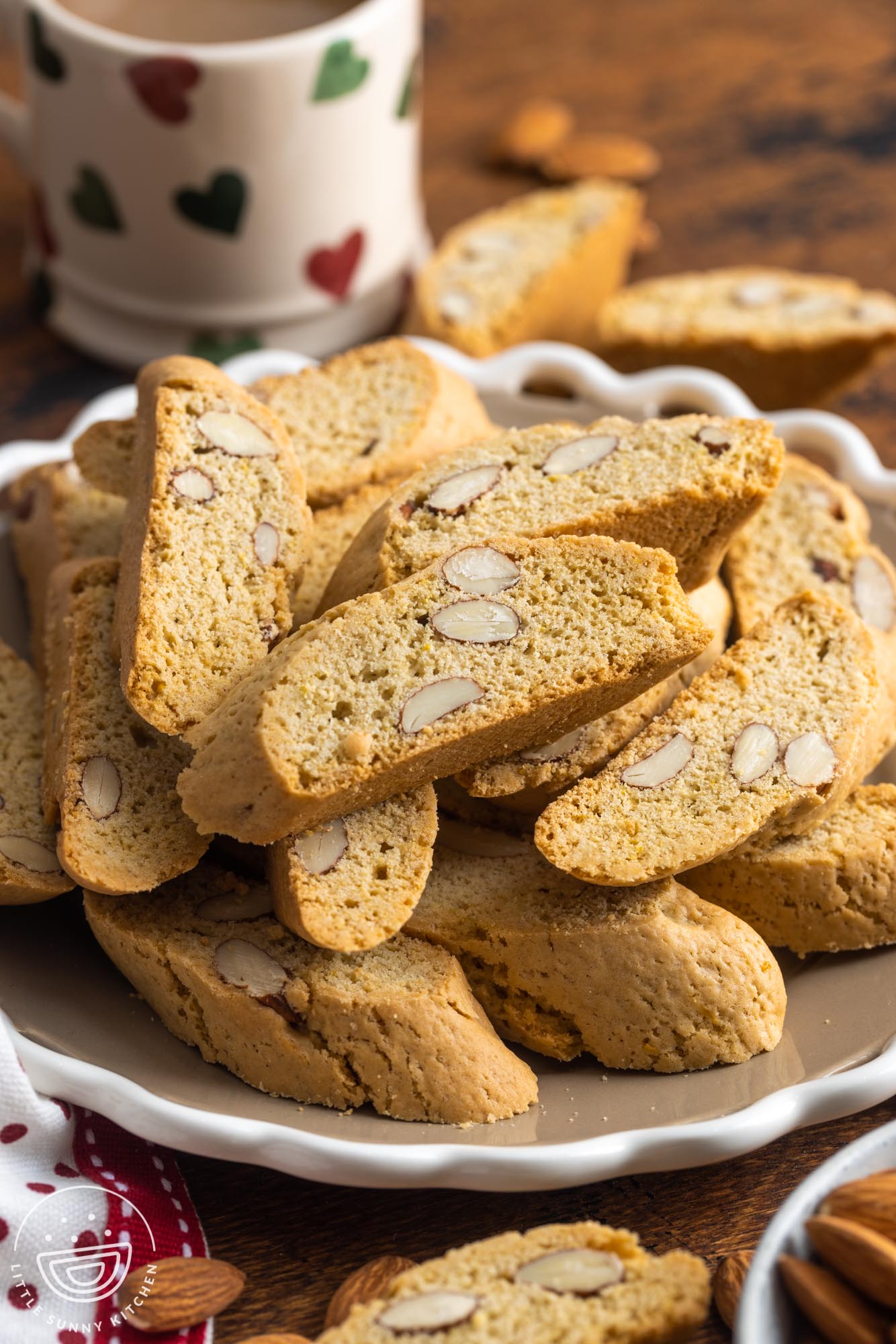 a plate of cantucci with whole almonds in front of a mug.