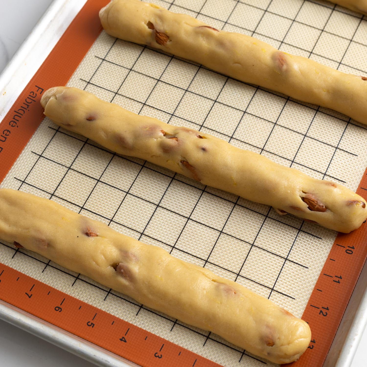 thin logs of almond biscotti dough on a silpat lined baking sheet.