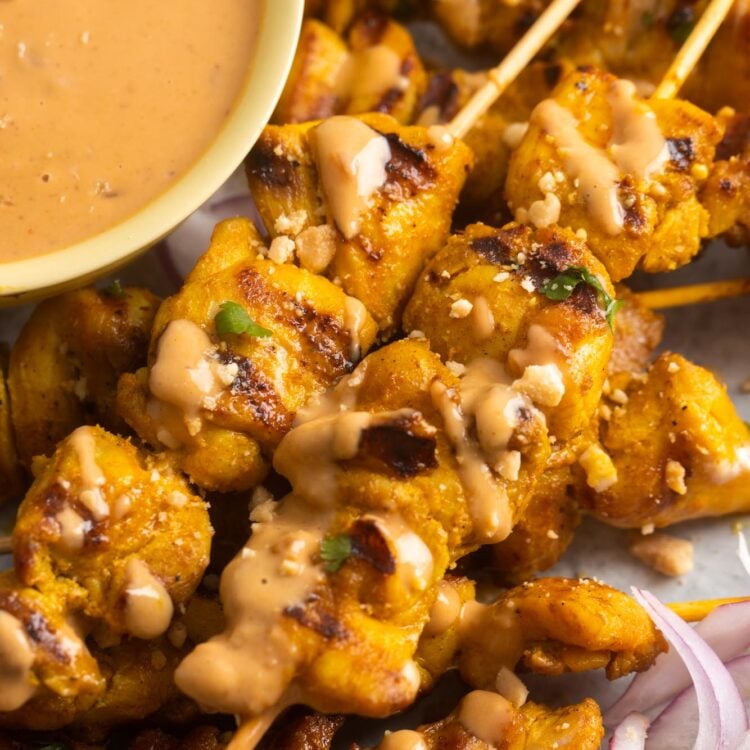 chicken satay skewers with a side of peanut sauce .