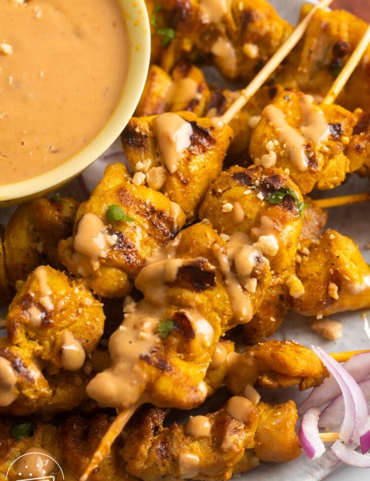 chicken satay skewers with a side of peanut sauce .