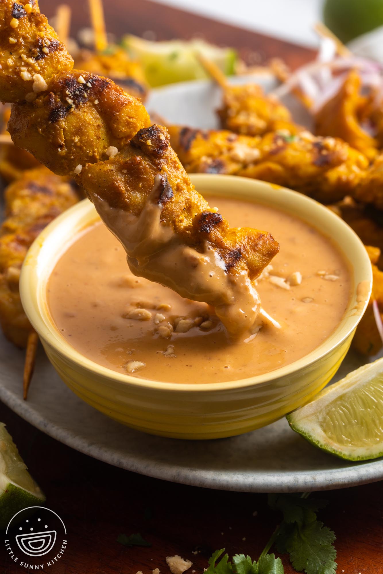 a chicken skewer dipped into peanut sauce.