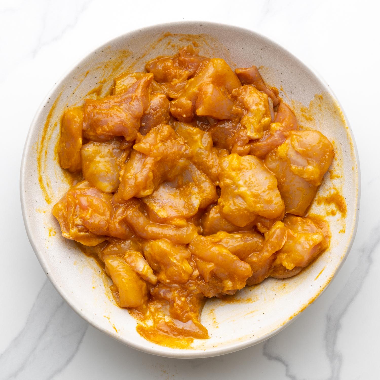 marinated meat for chicken satay in a white bowl.