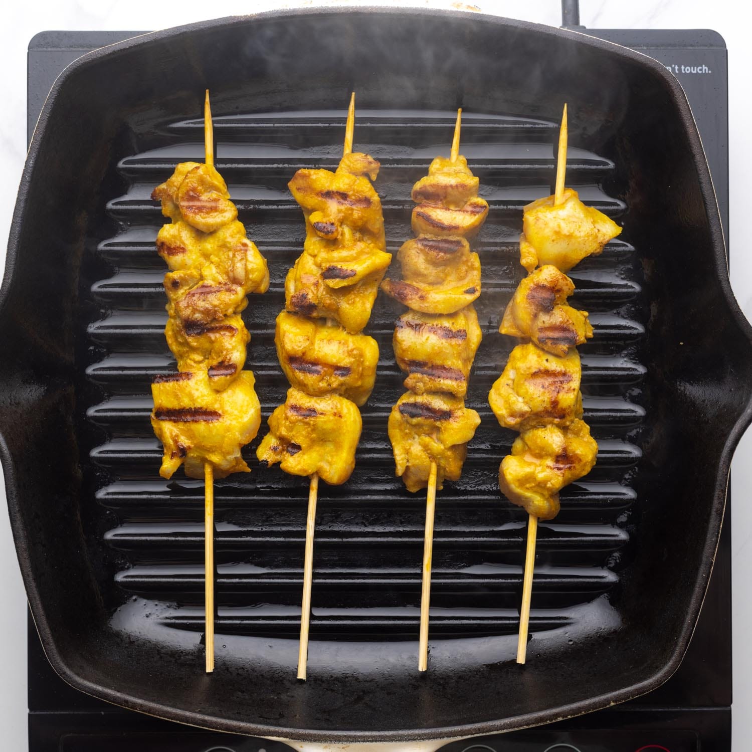 grilled chicken skewers in a cast iron grill pan.