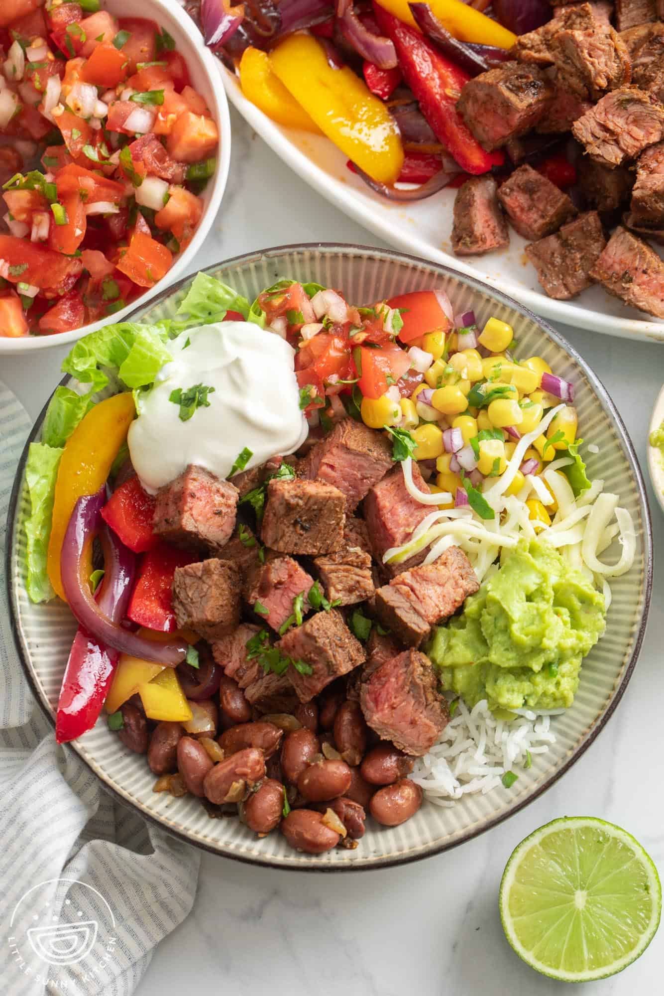 A rice bowl topped with chipotle steak, pinto beans, sour cream, veggies, and cheese.