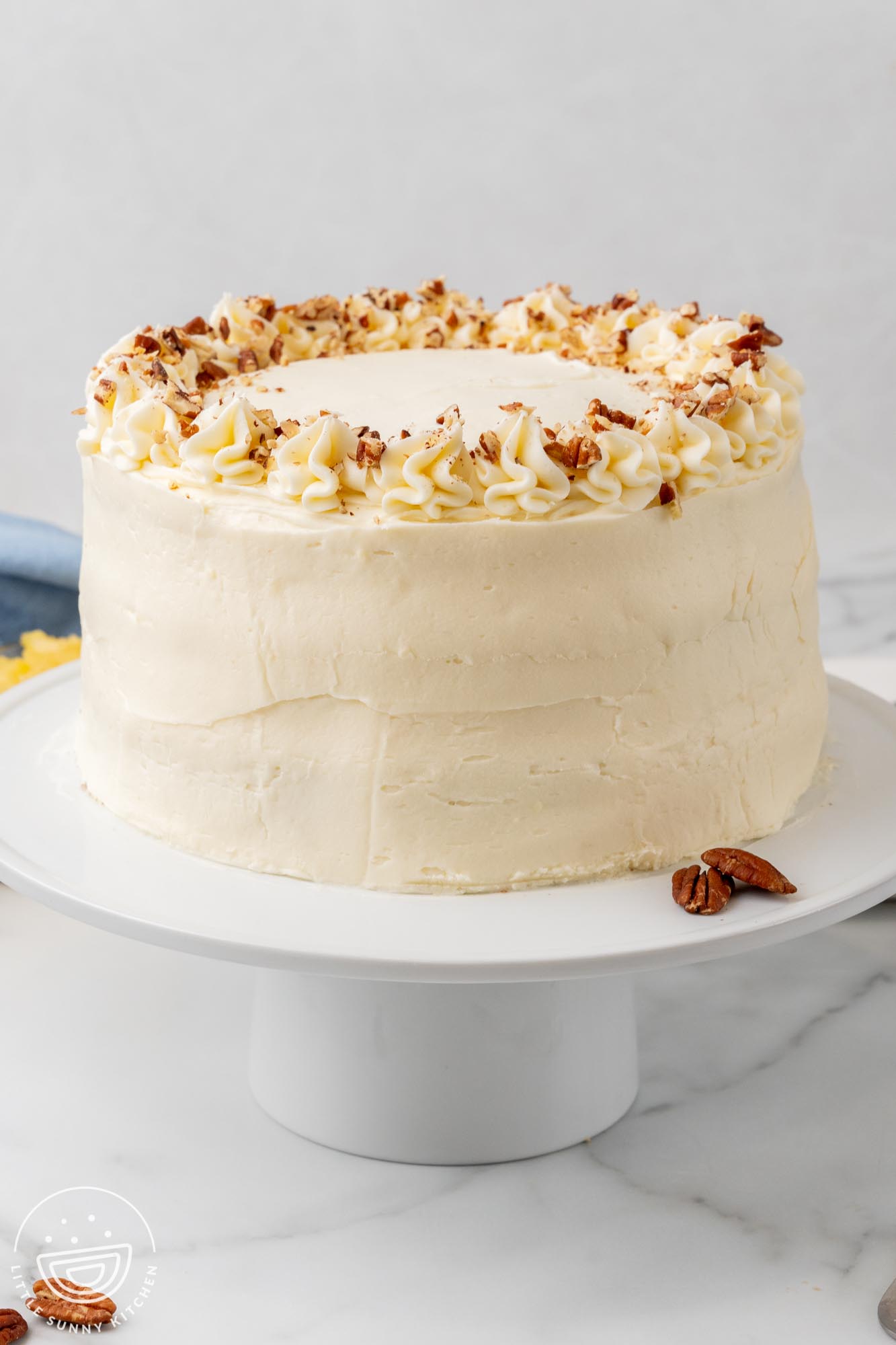 a tall, round hummingbird cake on a white cake pedestal.