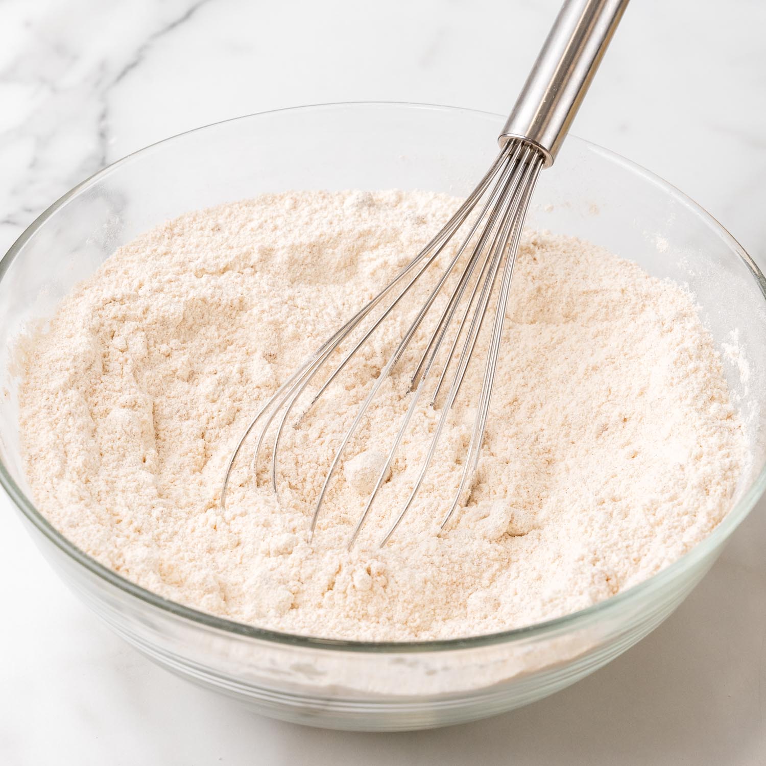 flour in a glass bowl with a whisk.