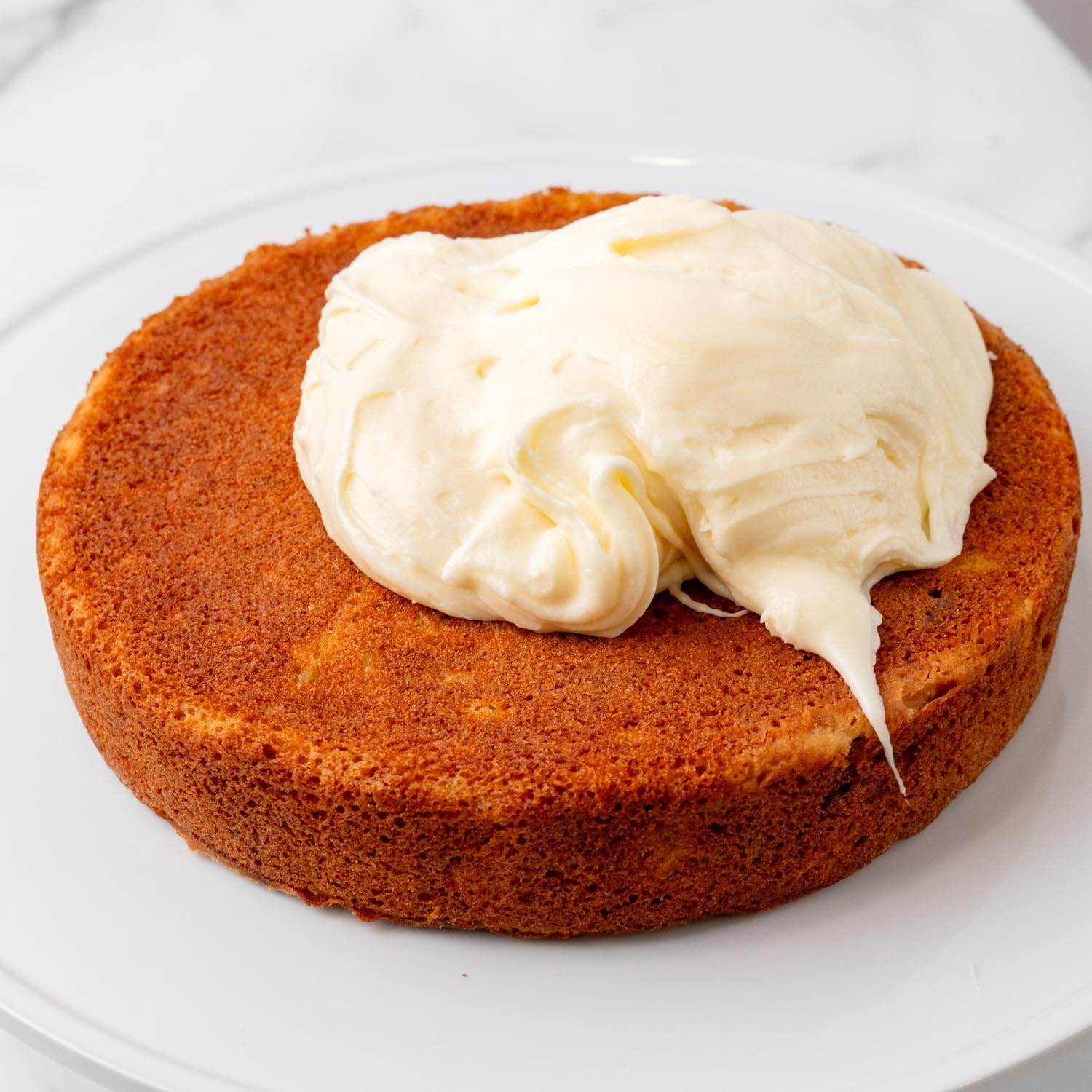 a large scoop of frosting on a single layer of hummingbird cake.