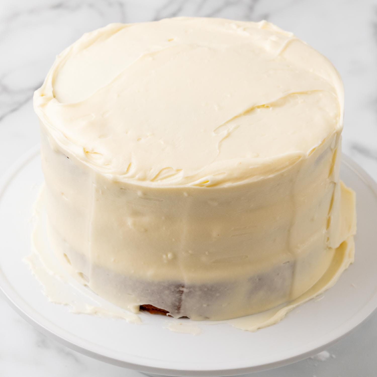 cream cheese frosting added to layered hummingbird cake.