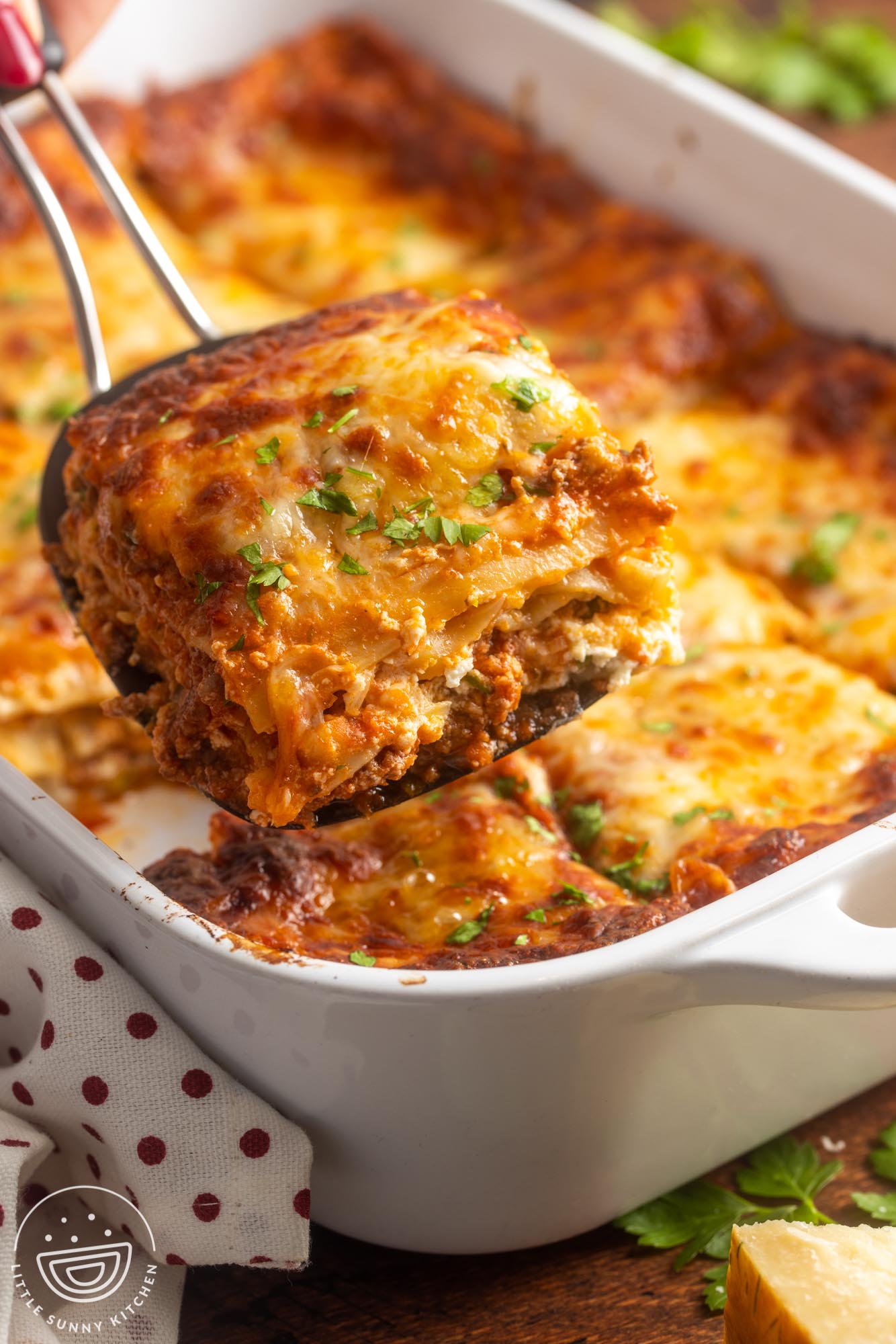 a spatula lifting out a piece of lasagna from a pan.