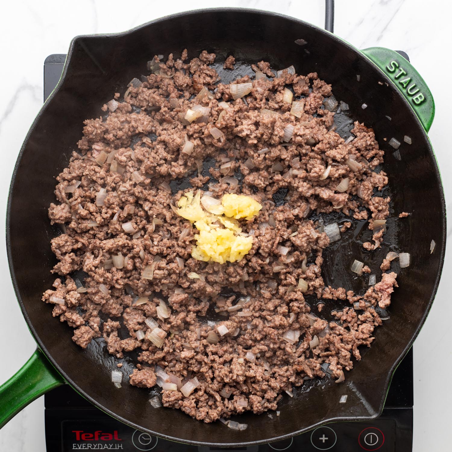 ground beef in a skillet with onion and garlic.