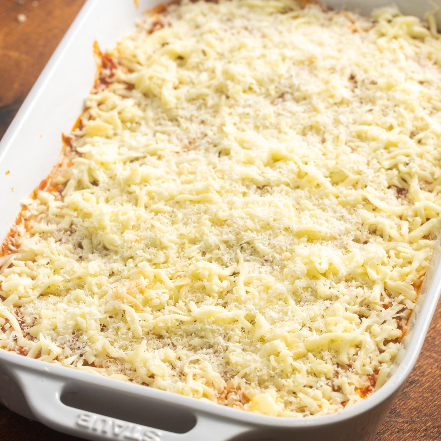 shredded cheese sprinkled over a pan of lasagna.