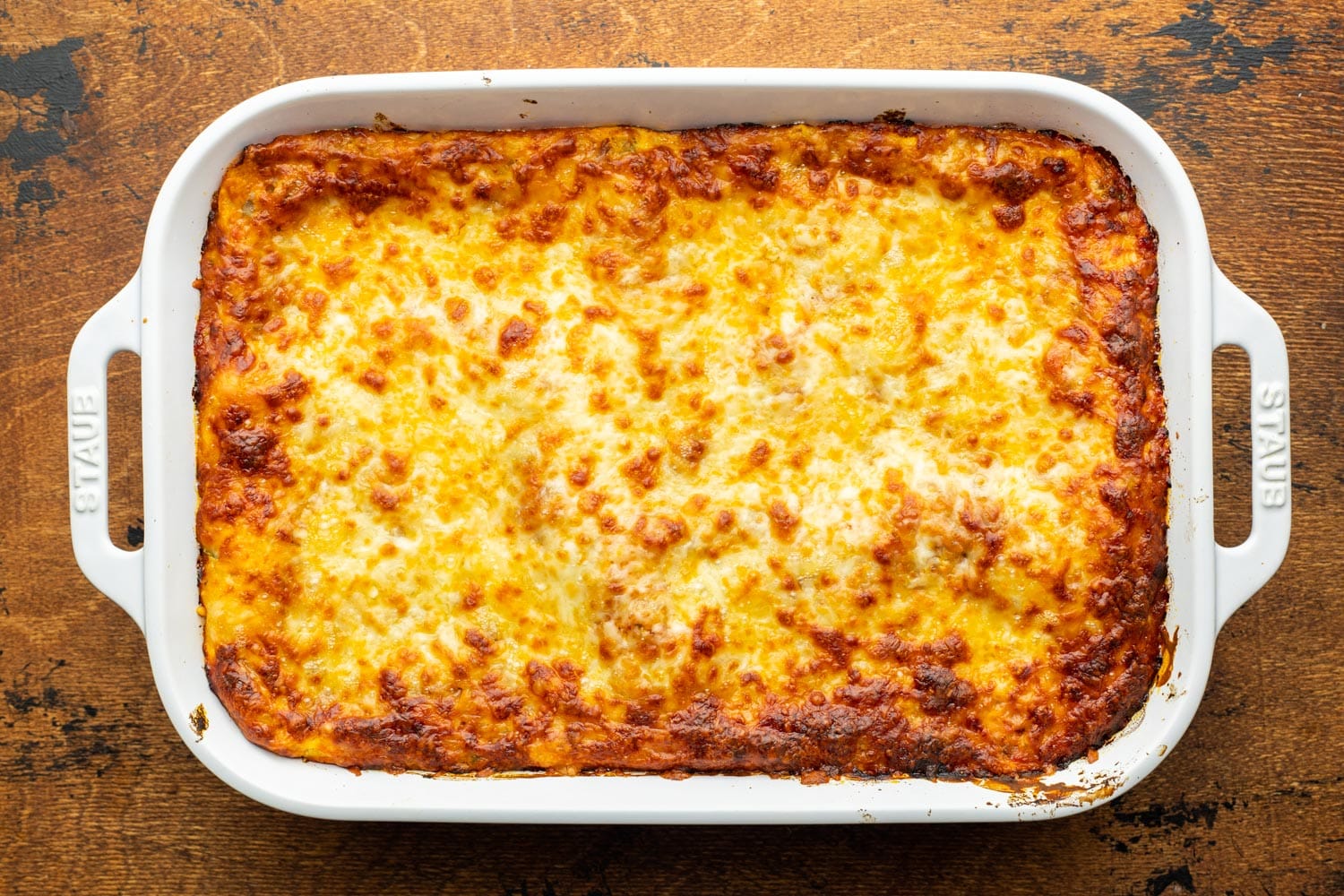 baked lasagna in a ceramic pan. The cheese is bubbly and browned on top.