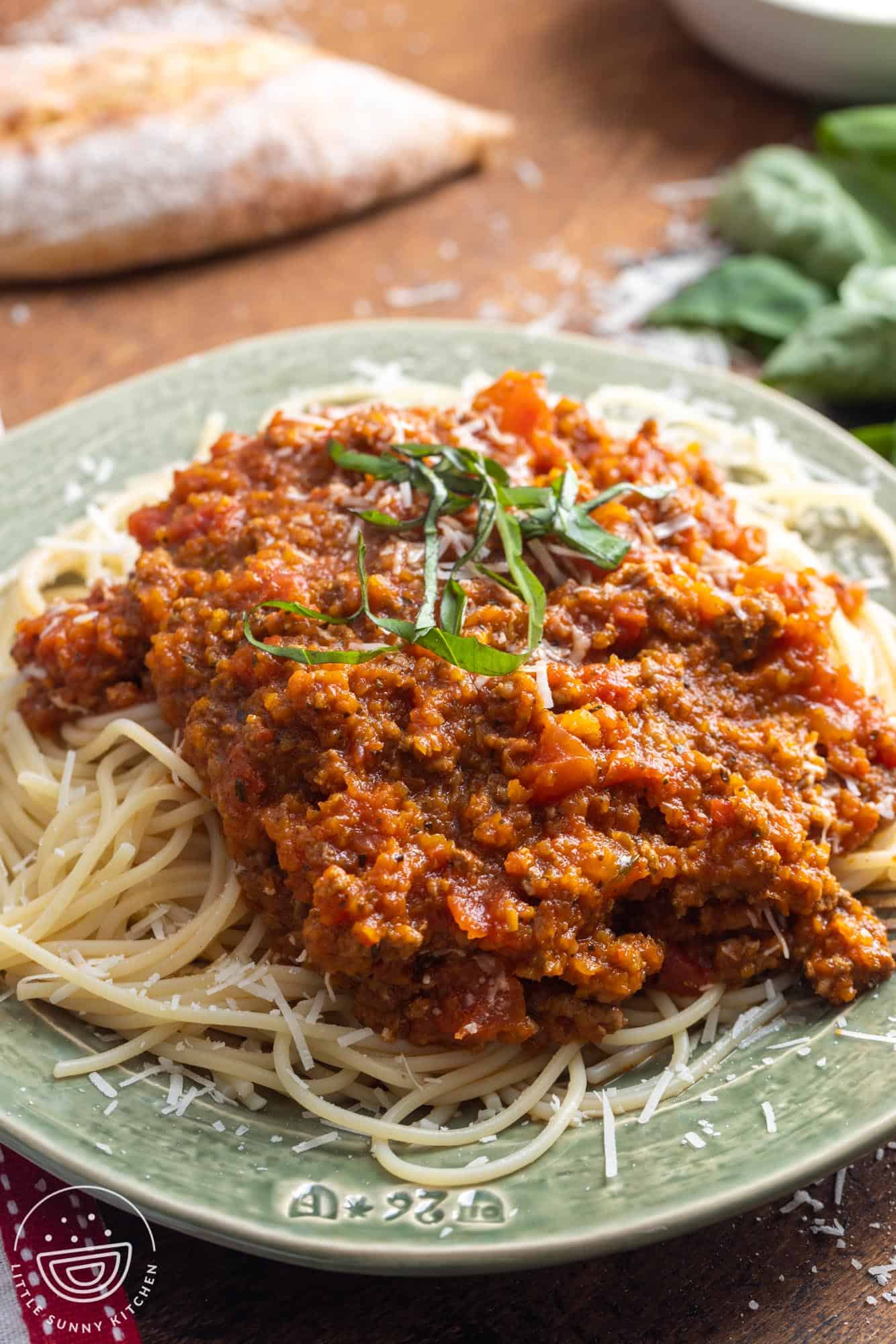 a light green plate of spaghetti and meat sauce with hidden vegetables.