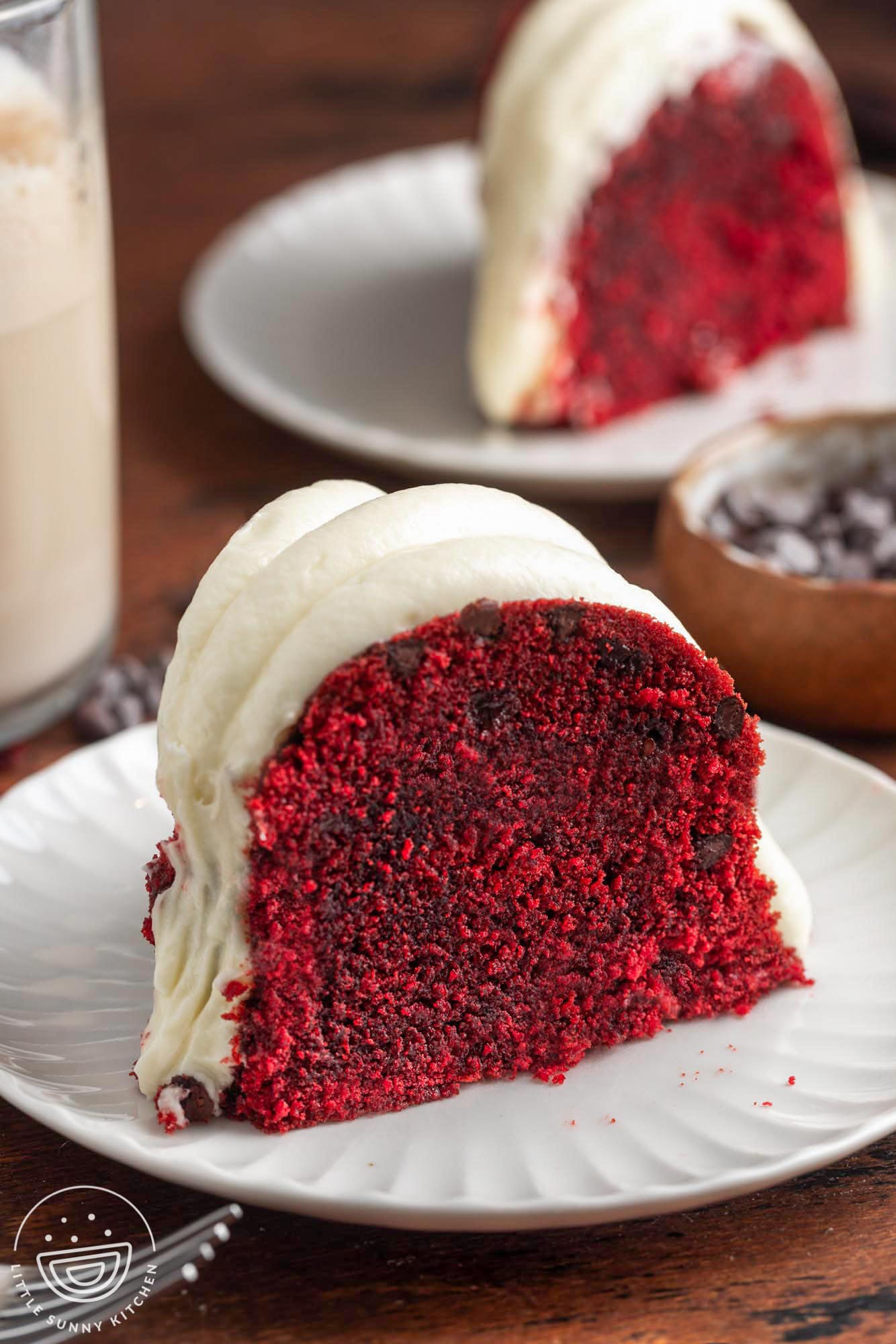 deep red velvet bundt cake on a plate, topped with icing.