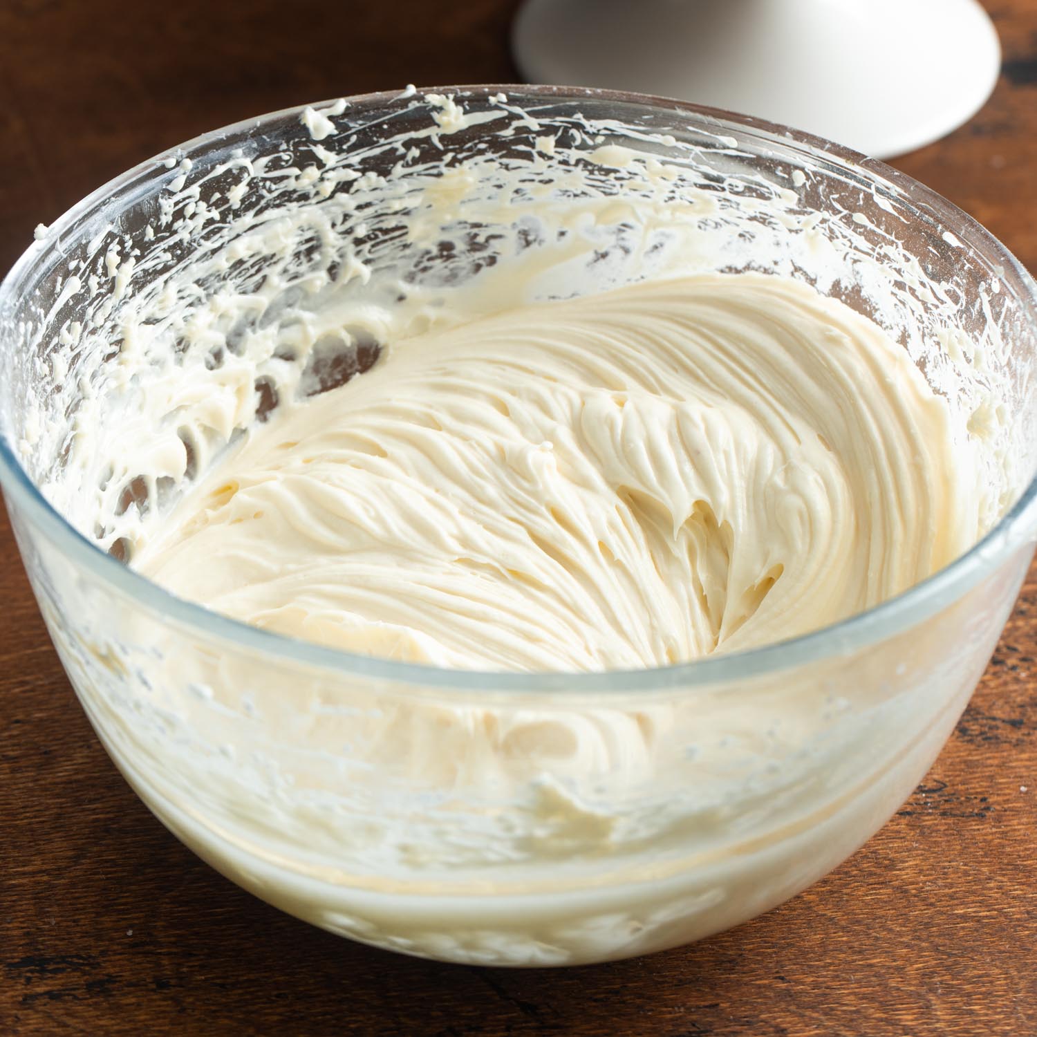 smooth cream cheese frosting in a glass mixing bowl.