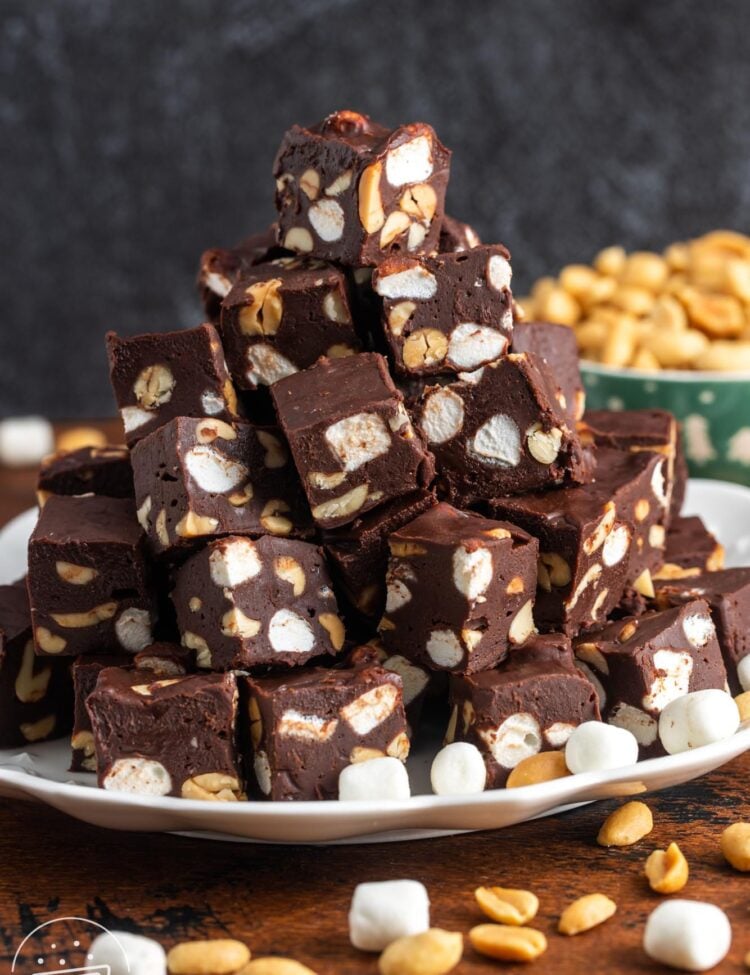 small cubes of rocky road fudge with marshmallows and nuts, stacked on a platter in a pyramid shape.