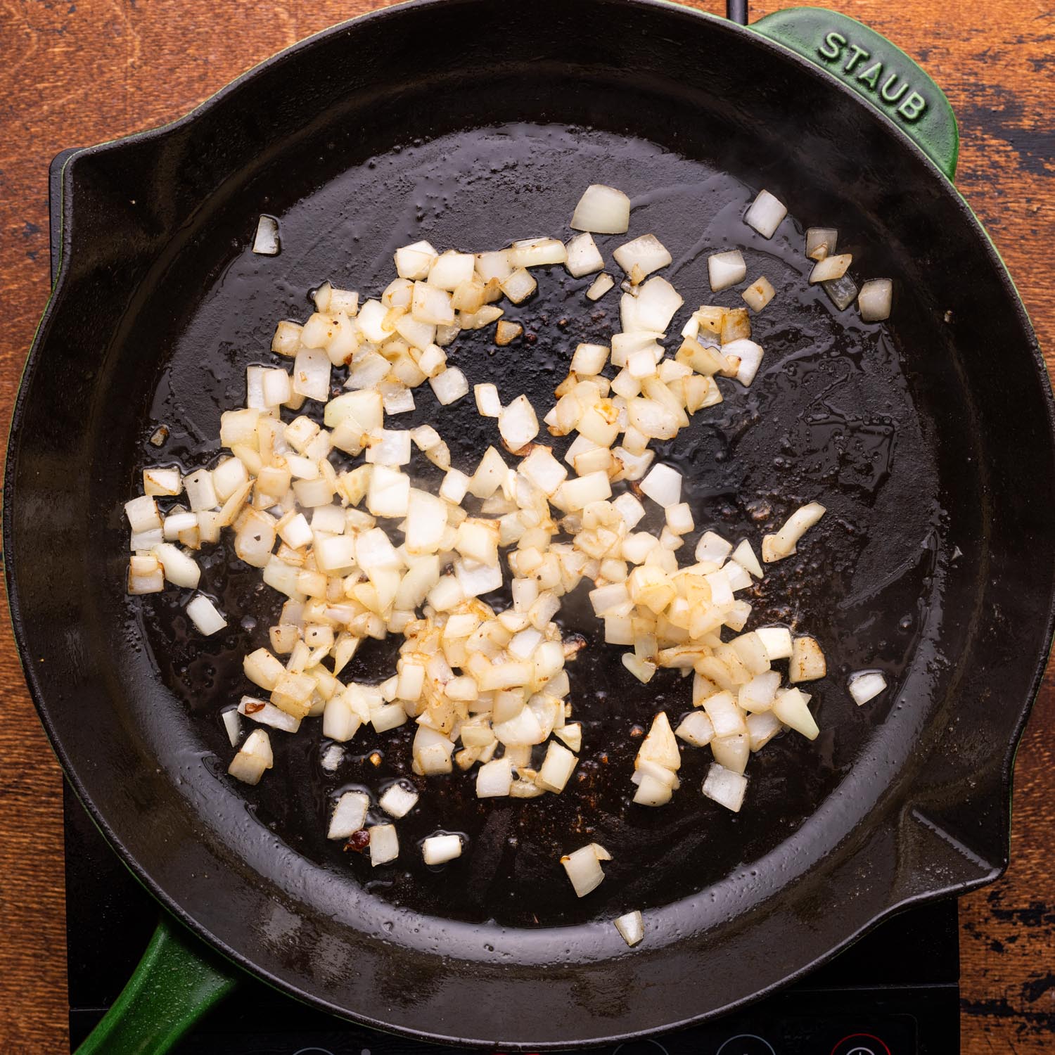 diced onions cooking in a cast iron skillet.