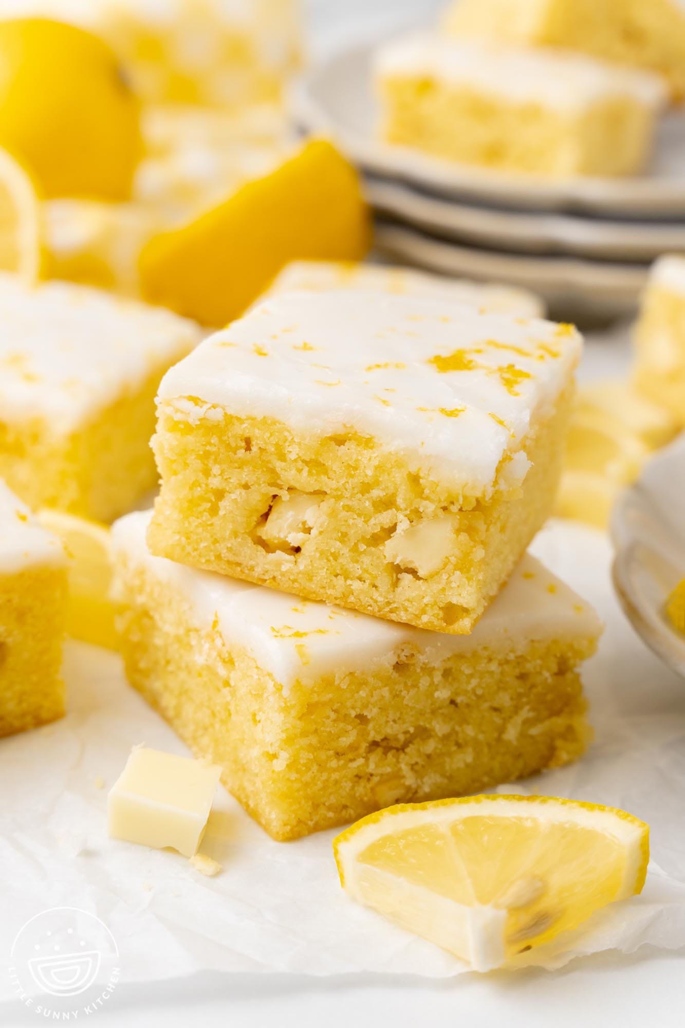 Two lemon brownies stacked on top of each other. You can see chunks of white chocolate inside of them.