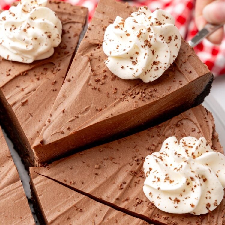 a no bake chocolate cheesecake cut into slices. One slice is being lifted up with a cake server.