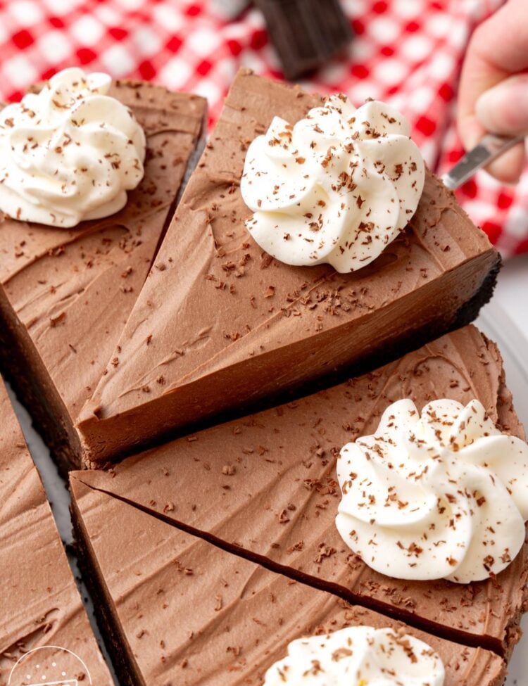 a no bake chocolate cheesecake cut into slices. One slice is being lifted up with a cake server.