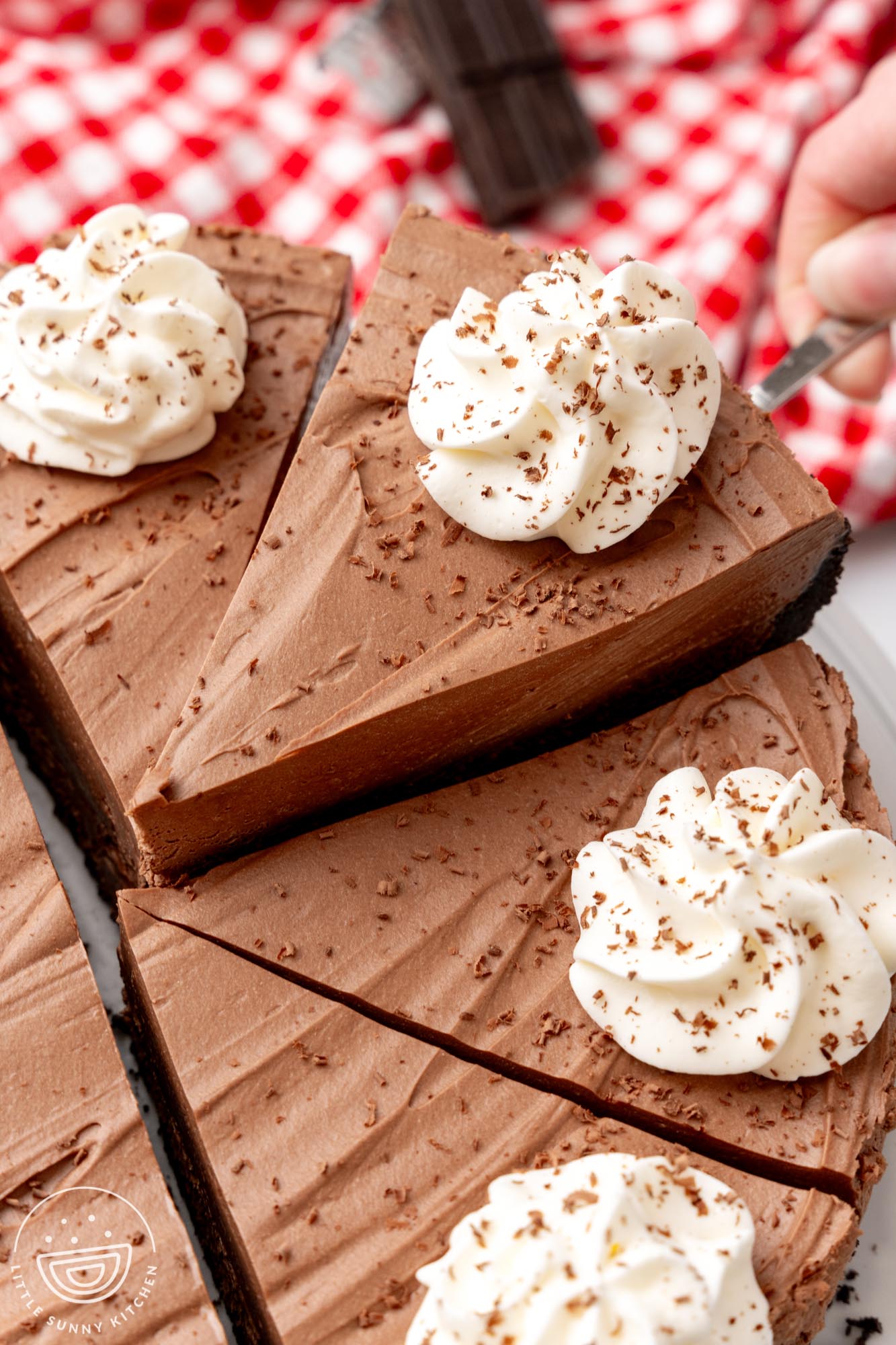 a no bake chocolate cheesecake cut into slices. One slice is being lifted up with a cake server.