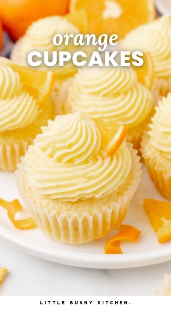 a plate of orange cupcakes with swirls or orange icing. Text overlay says "Orange Cupcakes" in white lettering.